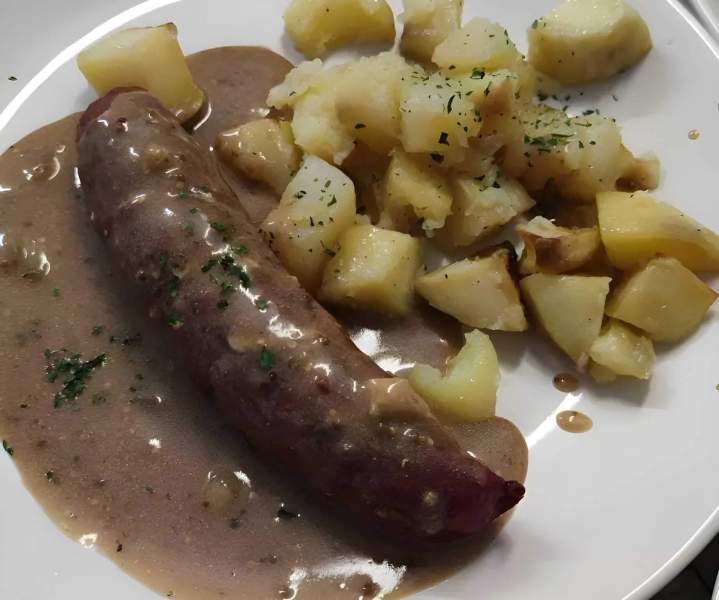 Andouillette servie avec une sauce et des pommes de terre sautées Cuissai